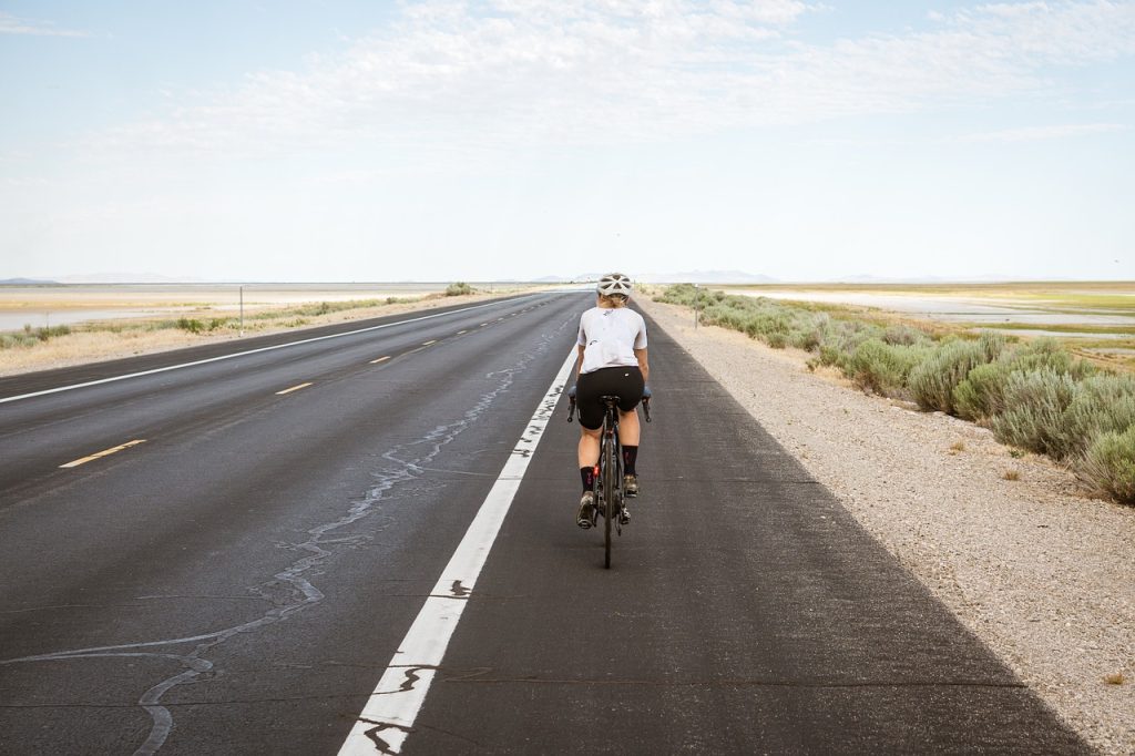 Cyclist riding along the shoulder of an open road